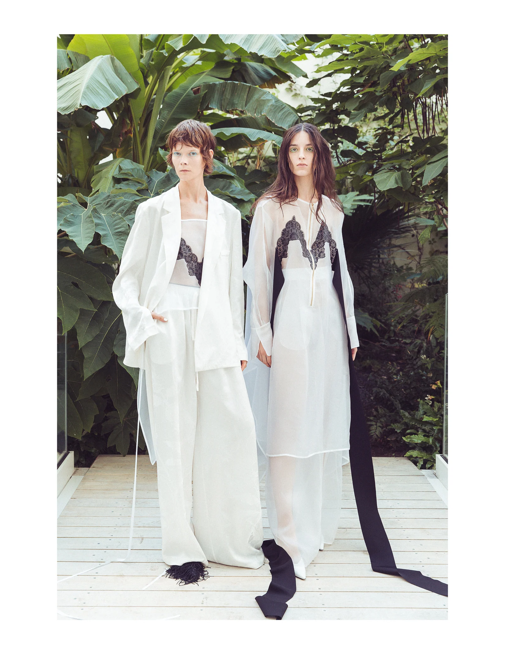 Two models in long flowing looks surrounded by foliage