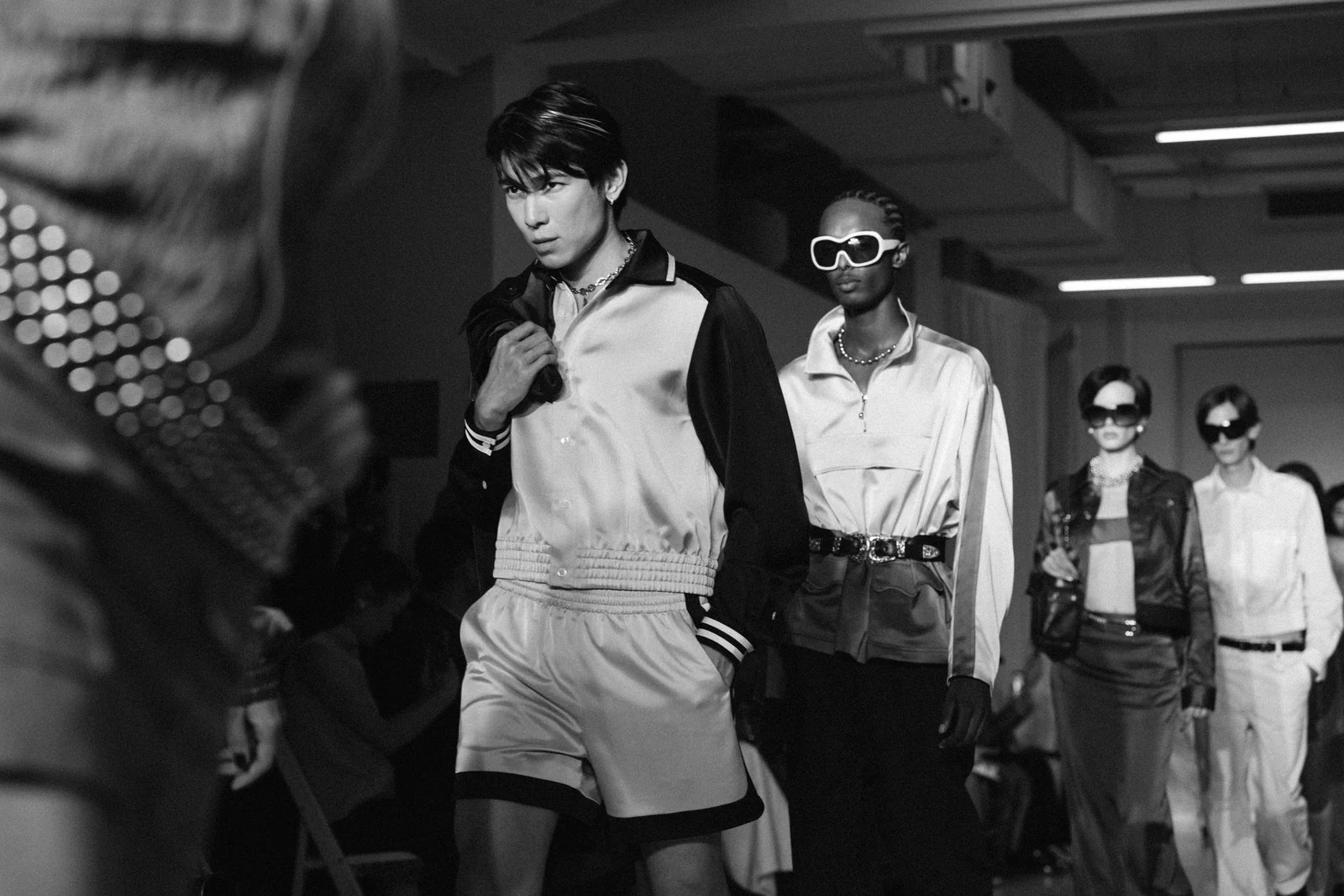 Private Policy — Black-and-white runway photograph of models in tailored looks